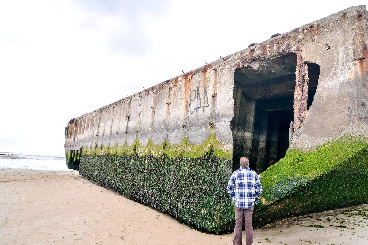 A man stands in front of a "Mulberry" at the artificial harbor at Arromanches.