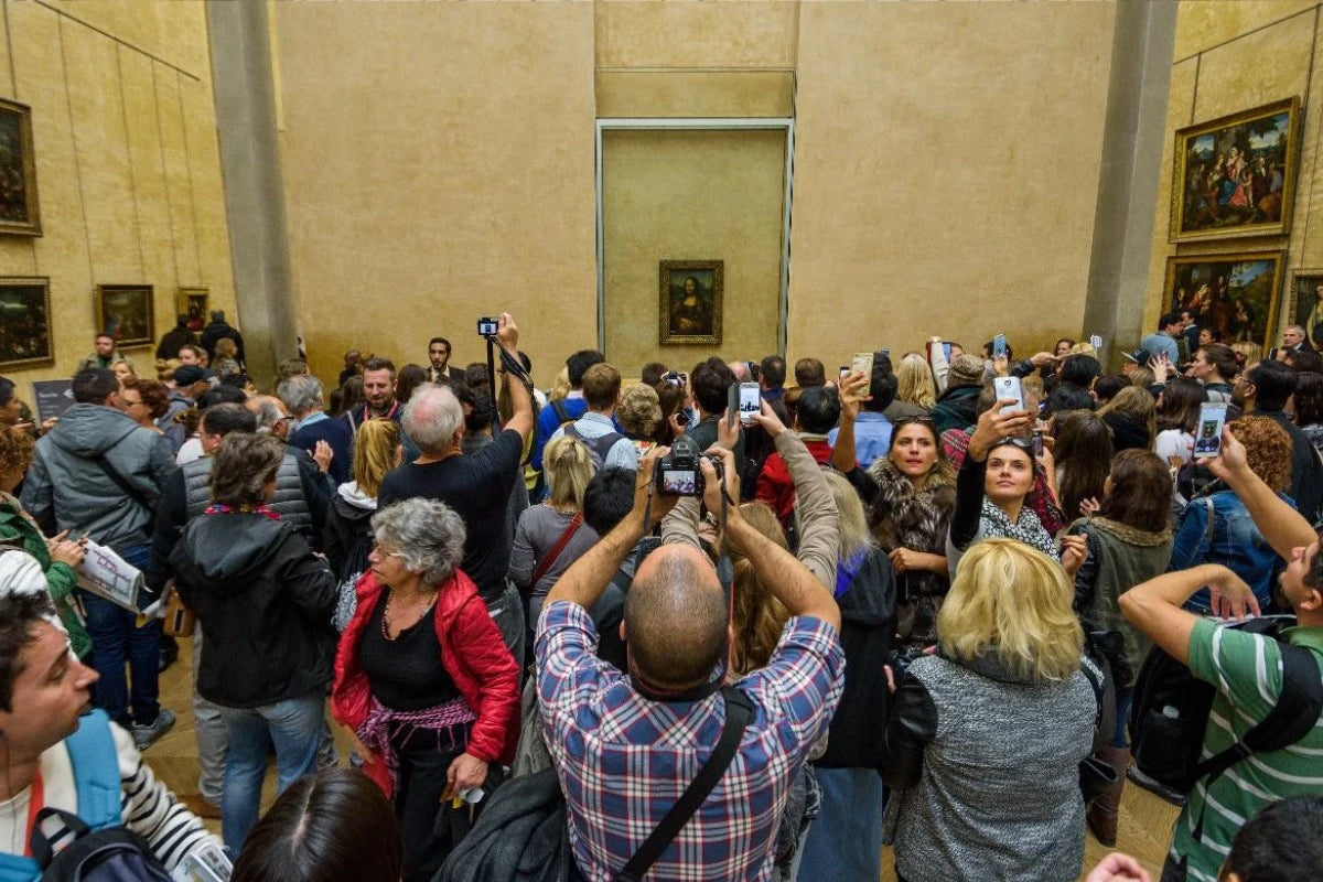 Tourists looking at the Mona Lisa in the Louvre.